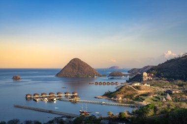 Güneşin doğuşunda Labuan Bajo, Komodo, Endonezya 'da nefis bir sahil cennetinin özünü kusursuz bir şekilde yakalayan nefes kesici sakin sular, güzel adalar ve lüks villalar.
