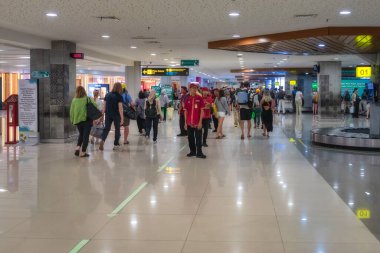 Bali, Endonezya 9 Ekim 2024 I Gusti Ngurah Rai Uluslararası havaalanı çeşitli yolcularla dolu, kontrol gişeleri ve hareketli havaalanı aktivitelerini vurgulayan bagaj atlıkarıncaları