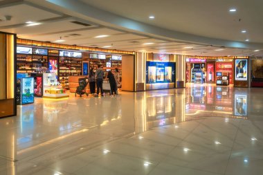 Bali, Indonesia, 9 Oct 2024 Modern shops in I Gusti Ngurah Rai International airport, scene featuring a stylish illuminated signage, and a diverse group of shoppers exploring multiple various stores clipart