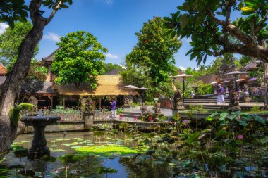 Bali, Endonezya, 10 Ekim 2024 Bu sakin Ubud Su Sarayı bahçesinde büyüleyici bir nilüfer havuzu, canlı yemyeşil bir gölet ve geleneksel sazdan çatı binaları sergileniyor, hepsi parlak, güneşli bir gökyüzünün altında güneşleniyorlar.