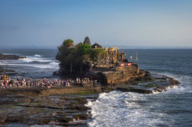 Bali, Endonezya, 10 Ekim 2024 Tanah Lot Tapınağı 'ndaki çarpıcı günbatımına tanık olun. Bali' nin ünlü bir deniz tapınağı. Dalgalar ve kutsal Pujawali töreni için toplanan insanlar.