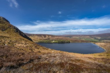 Sakin Bray gölü, yumuşak tepeler ve gür yeşillikler arasında, berrak mavi gökyüzünün altında, huzur ve rahatlama arayışında doğa severler için cennet gibi bir kaçış yaratır, Wicklow, İrlanda