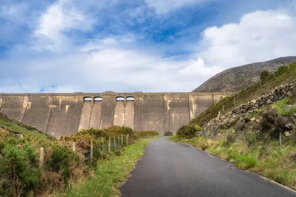 Mourn Dağları 'ndaki etkileyici Sessiz Vadi Barajı' na giden dolambaçlı bir yol. Renkli gökyüzü ile dolu canlı manzaralarla dolu. Açık hava meraklıları için mükemmel, Kuzey İrlanda.