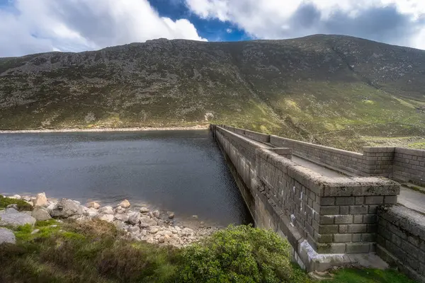 Berrak gökyüzünün altındaki yuvarlanan yeşil tepelere uzanan Sessiz Vadi Barajı 'nın nefes kesici manzarası. Mükemmel bir şekilde sergilenen doğal sakinlik ve huzur, Kuzey İrlanda.