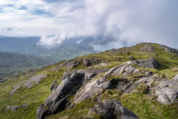 Kayalık Slieve Foye dağının tepesinden nefes kesici bir manzara, aşağıdaki yemyeşil vadileri sergiliyor ve yukarıdaki bulutlar huşu uyandıran doğal bir ortamda dönüyor, Carlingford, İrlanda