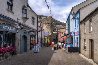 Carlingford, İrlanda, 04 Temmuz 2021 Renkli binalar, büyüleyici kafeler ve güzel bir sahil kasabasında çiçek açan çiçeklerle dolu güzel, canlı bir ara sokakta sakin bir yürüyüş yapın.