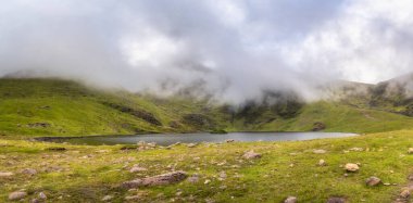 Havada süzülen yumuşak, sisli bulutlarla yemyeşil tepelerin arasında yuva yapmış sakin bir gölün nefes kesici manzarası doğanın olağanüstü güzelliğini gözler önüne seriyor, Kerry, İrlanda