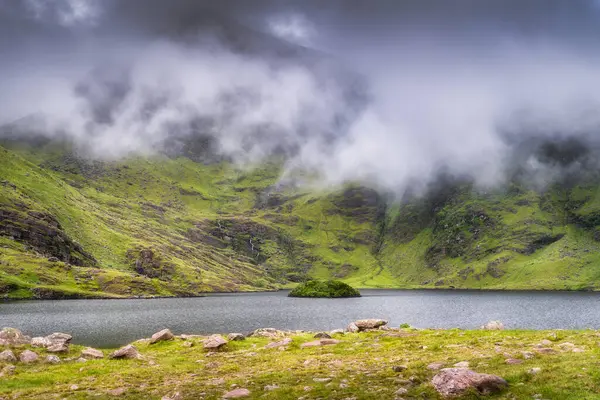 Güzel ve sakin bir Carrauntoohil dağı gölü, buğulanmış yemyeşil tepelerin arasına kurulmuş, herkesin zevk alması için huzurlu ve pitoresk bir doğal manzara sunuyor, Kerry, İrlanda