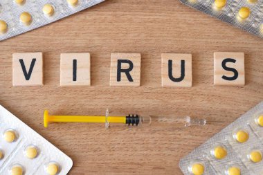 Virus word with syringe and medicines at the table