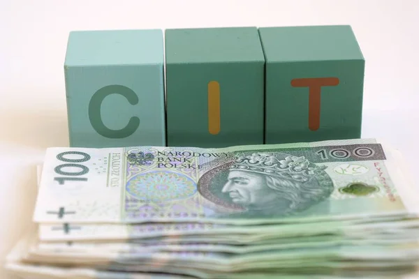 stock image CIT word in Polish language. Name for corporate tax in Poland. Polish zlotych in cash at the table