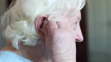 İşitme cihazı - işitme cihazı takan ve gülümseyen yaşlı kadın.