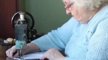Yaşlı kadın Neuman dikiş makinesine dikiş dikiyor..