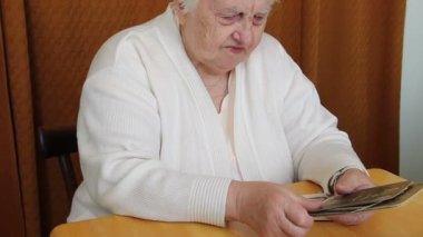 Yaşlı kadın ailesinin eski fotoğraflarını izliyor.