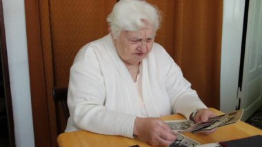 Yaşlı kadın ailesinin eski fotoğraflarını izliyor.