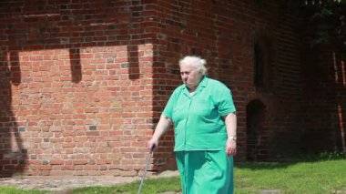 Yaşlı kadın bastonla yürüyor..