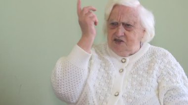 Çok kızgın yaşlı bir kadın birine parmağını sallıyor.