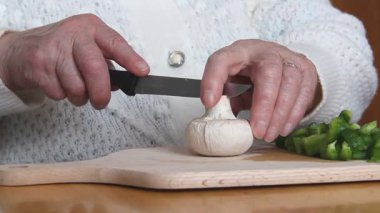 Mantar doğrayan ve vejetaryen yemeği hazırlayan yaşlı kadın.