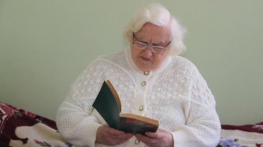 Yaşlı bir kadın kitap okuyor. 