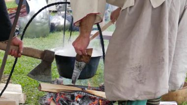 Ortaçağ kıyafeti giyen insanlar yemek pişiriyorlar.