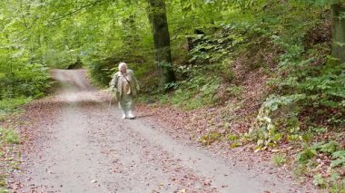 Orman parkında yürüyüşte bastonu olan yaşlı kadın