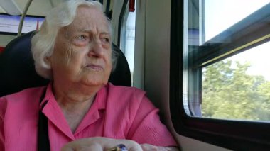 Yaşlı kadın bir tren penceresinde bakar