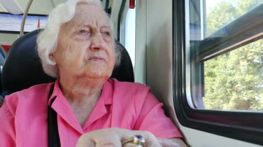 Yaşlı kadın bir tren penceresinde bakar