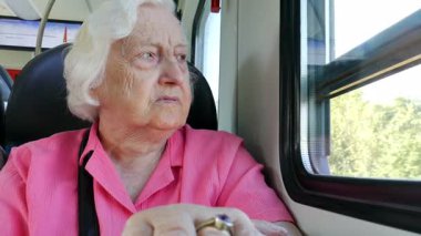 Yaşlı kadın bir tren penceresinde bakar