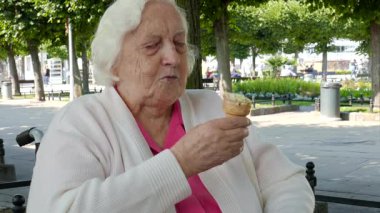 Tekerlekli sandalyede kıdemli kadın bir parkta dondurma yiyor