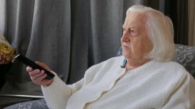 Yaşlı, kıdemli kadın evde televizyon izliyor. Yakın çekim