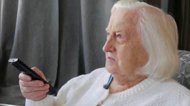 Yaşlı, kıdemli kadın evde televizyon izliyor. Yakın çekim 