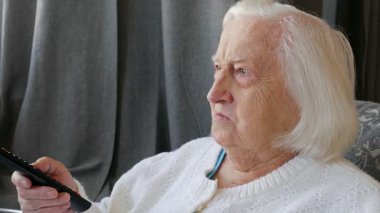 Yaşlı kadın evde Tv izliyor ve sonraki kameraya gülümsüyor