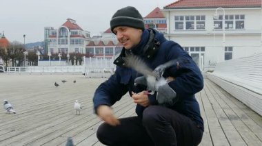 Adam rıhtımda kuşları besliyor.