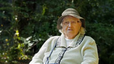 Parkta tekerlekli sandalyede yaşlı kadın