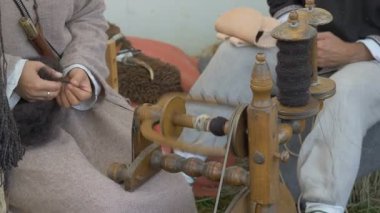 Kadın dönen çarkın üzerinde yün örüyor.