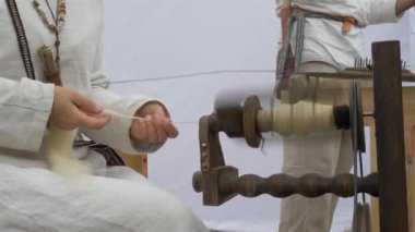 Dönen tekerlek. Kadın yün örüyor ve yün bir halı gösteriyor..