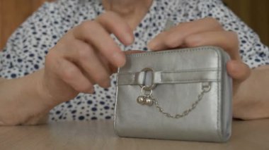 Yaşlı bir kadın bütün parasını cüzdanından atıyor.