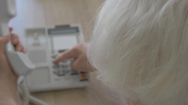 Yaşlı kadın bir telefon görüşmesi yapıyor.