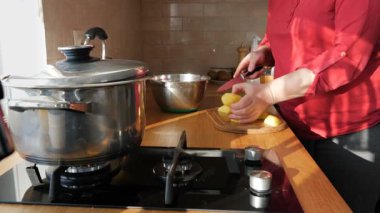 Kadın beyaz patatesleri kesme tahtasında kesiyor. Çorba pişirme