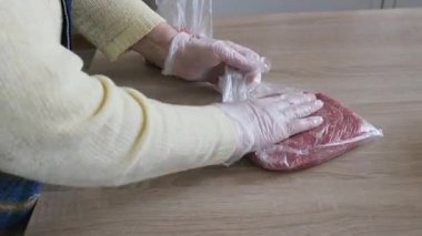 Yaşlı kadın doğranmış eti dondurucuya koyuyor.