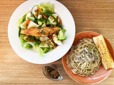 Mantarlı makarna, sebze salatası ve ahşap arka planda ızgara somon. Yüksek kalite fotoğraf