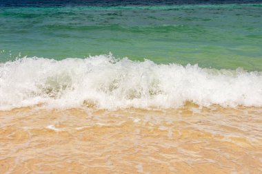 Kumsalda, dağların ve denizin zemininde sarı kumlar olan yumuşak dalgalar. Yüksek kalite fotoğraf