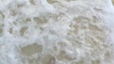 Tek başına, deniz dalgalarıyla yıkanmış kumlu bir plajda yalınayak yürüyor. görüntüler