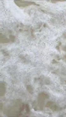 Tek başına, deniz dalgalarıyla yıkanmış kumlu bir plajda yalınayak yürüyor. görüntüler