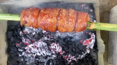 Lechon göbeğini geleneksel şekilde kızartıyorum. Bambu tükürüğünün üzerine bir parça domuz eti.. 