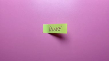 Bir el, üzerinde pembe bir arkaplan olan bir çıkartmayı soyar..
