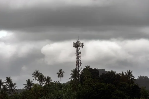 wireless data station against the background of a cloudy sky on a mountain in the jungle. Cell tower.