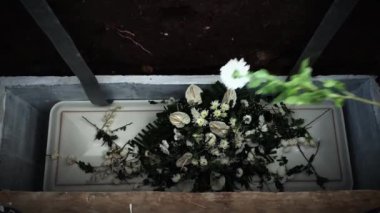Tabut kapağındaki çiçekler mezara atılır. Cenaze