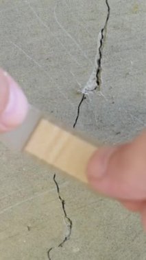 Beton duvardaki çatlağa bir yama yapışmış. Vicdansız tamir konsepti.