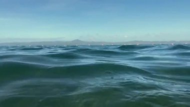 Denizin alçak açılı görüntüsü dağlar ve gökyüzünün arka planına karşı.. 