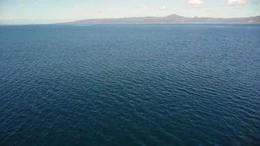 Dağların ve gökyüzünün arka planına karşı okyanus yüzeyinin drone görüntüsü.